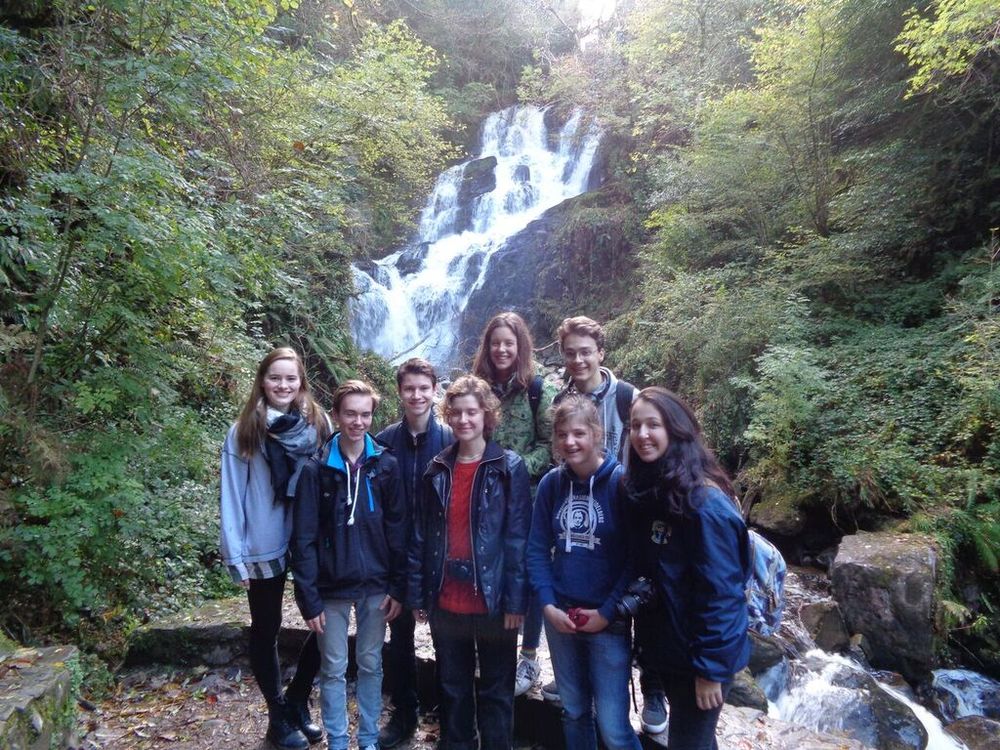 Austauschschüler mit Freunden vor Wasserfall in Irland